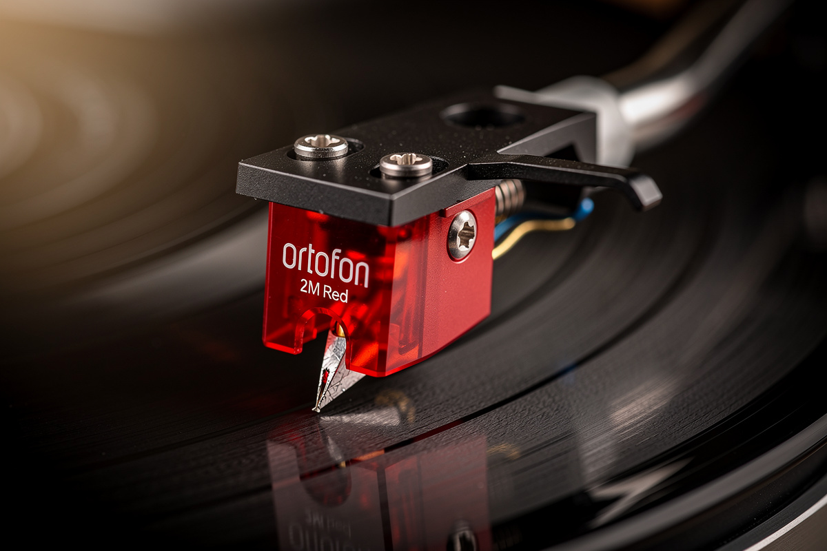 Ortofon 2M Red phono cartridge mounted on tonearm above a record groove