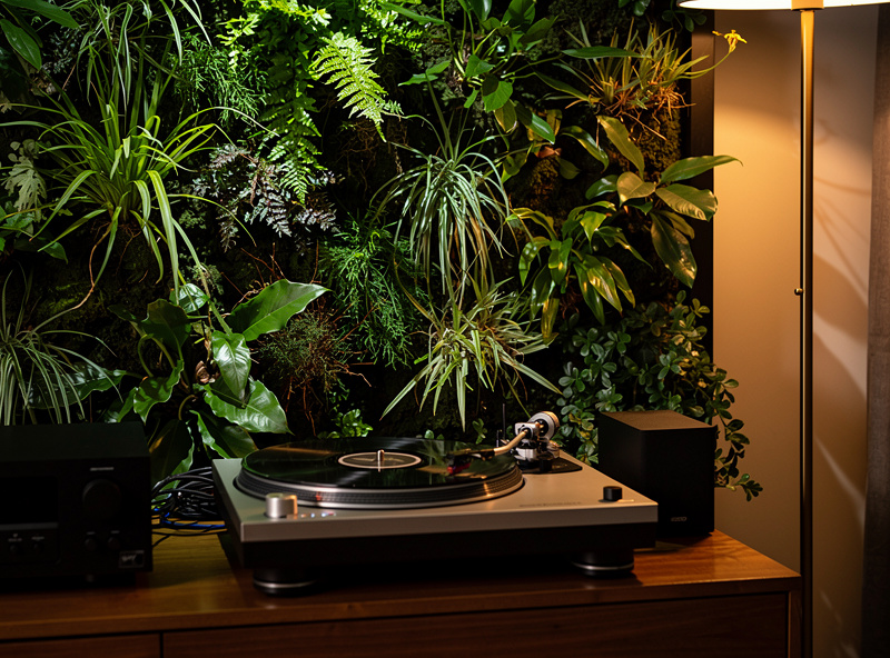 Vertical living plant wall installation behind a turntable setup with floor lamp lighting