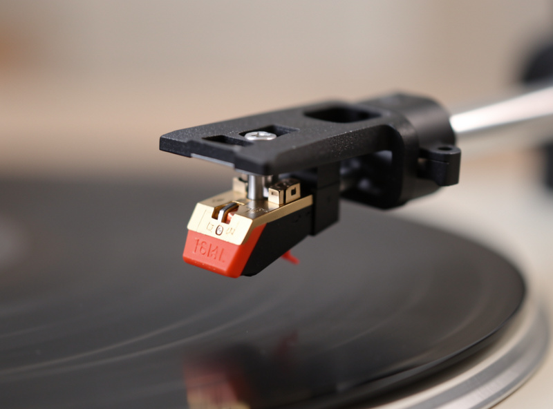 Close-up of a moving-magnet cartridge and headshell on a turntable tonearm ready for upgrade