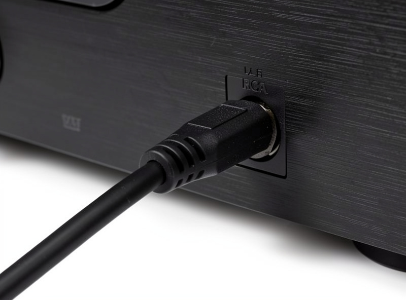 A single LFE cable running from an AV receiver subwoofer output to the input on a powered home theater subwoofer