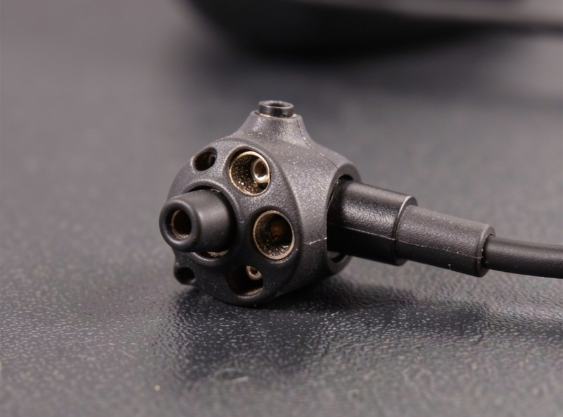 Macro close-up of a multi-driver in-ear monitor shell showing the nozzle and detachable cable connector